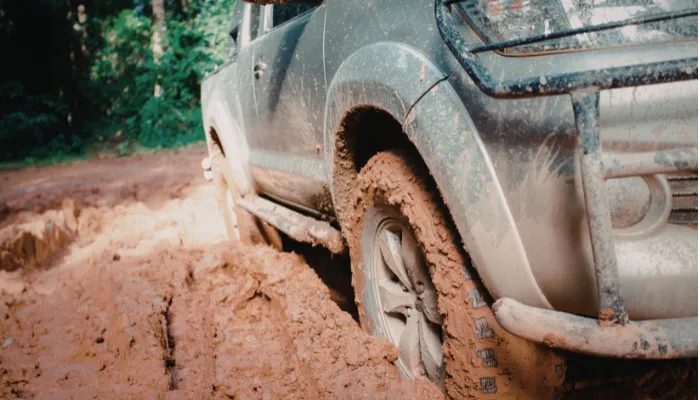 A 4x4 truck navigating deep mud on an off-road trail, illustrating the extreme conditions tested in our Toyo Open Country A/T III vs Falken Wildpeak AT4W comparison